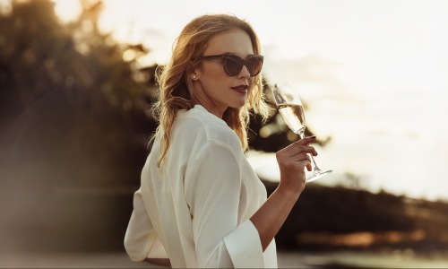 a woman sipping on wine outdoors in a bright dress